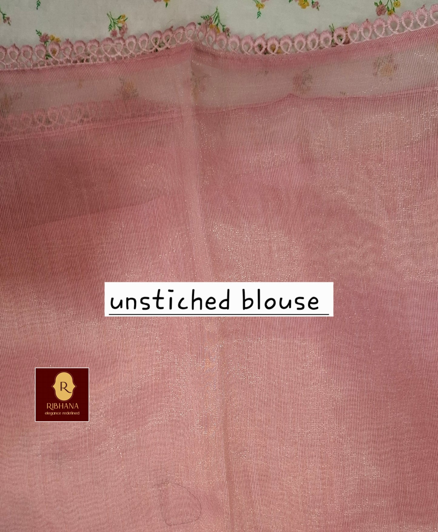 A dusty pink unstitched cotton blouse fabric with a subtle woven texture, featuring a decorative floral lace border at the top and a white text overlay reading 'unstitched blouse'. A small brand logo for Ribhana is visible in the bottom-left corner.